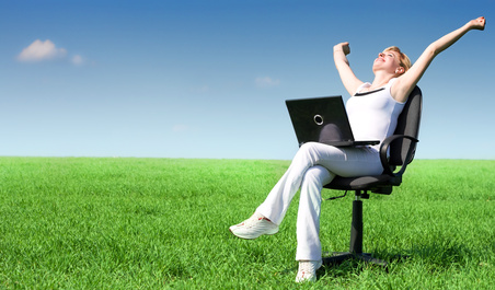 Excited blonde with a laptop in a meadow